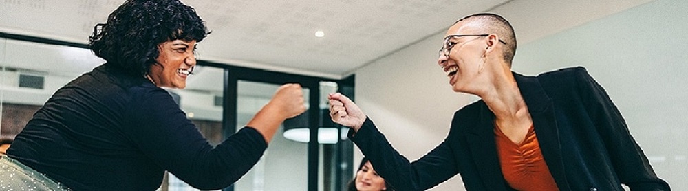 Colleagues fist pumping over a conference table Colleagues fist pumping over a conference table