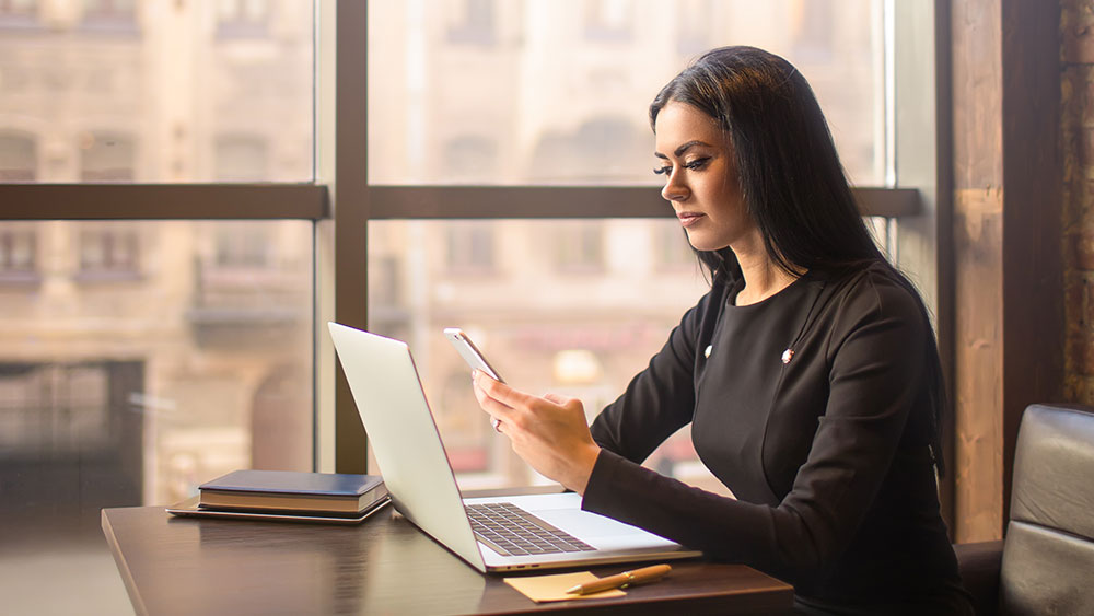 Professional woman uses mobile phone to check accounts on open banking platform Professional woman uses mobile phone to check accounts on open banking platform