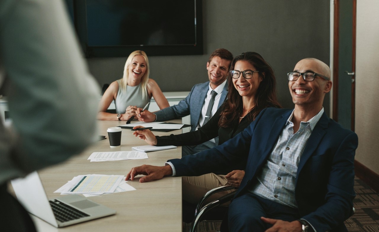 Professionals sitting around desk and smiling