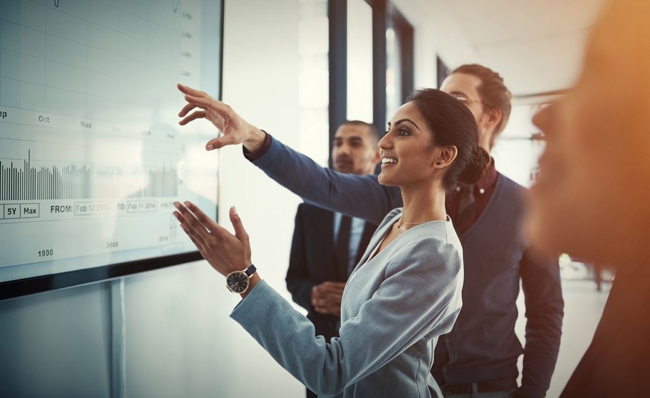 Team discussing data displayed on a screen in a boardroom