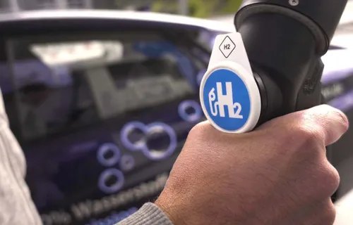 Hand hält einen Wasserstofftankschlauch in der Hand