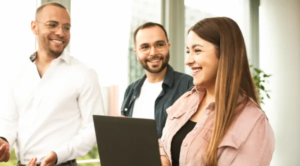 Drei CGI Member kommen mit einem Laptop in der Hand aus einer Besprechung