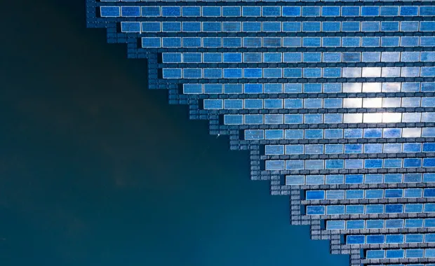Aerial view of floating solar panels arranged in a geometric pattern on a body of water