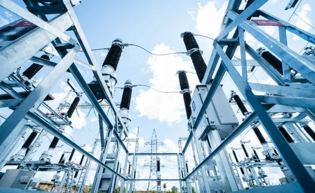 High-voltage electrical substation with steel framework and insulators under a blue sky