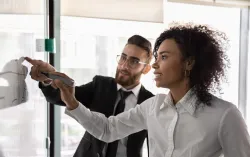 deux consultants pointant vers des points de planification stratégique sur un tableau blanc