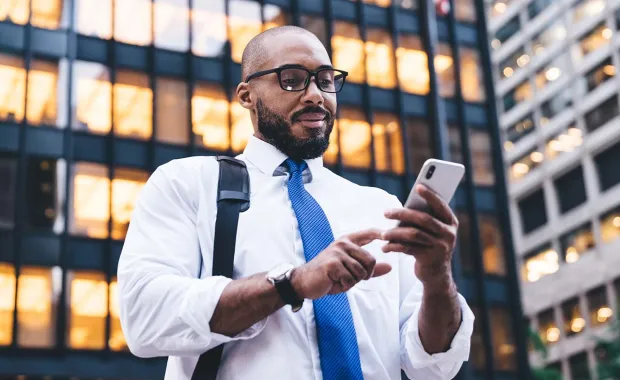 person using mobile phone in front of office building