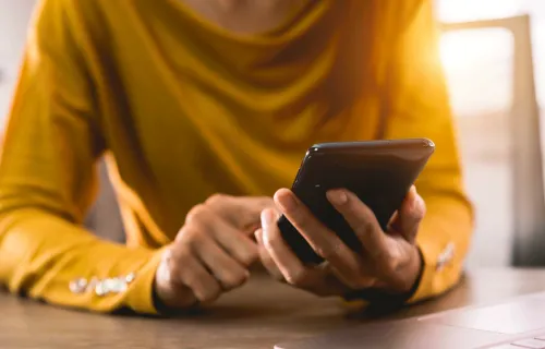 person holding mobile phone and touching screen with finger