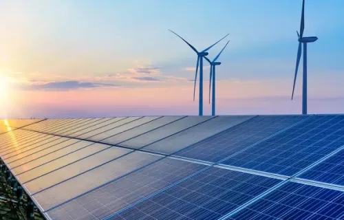 solar panels at sunset with wind turbines in the background