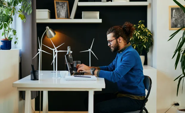 man sitting at desk with windmill figurines