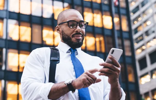 personne utilisant un téléphone portable devant un immeuble de bureaux