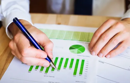 Professional reviewing graph with pen in one hand