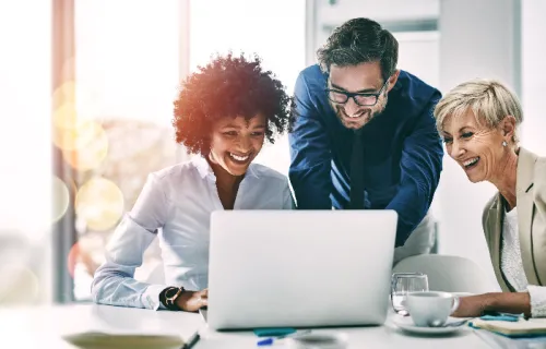 Three professionals looking at laptop screen