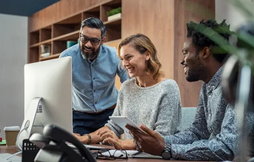 Three professionals looking at a computer screen
