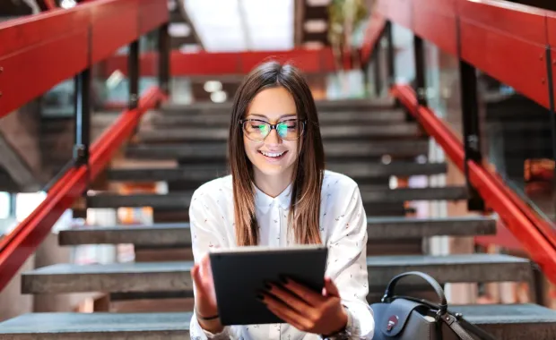 person sitting on stairs working on a tablet