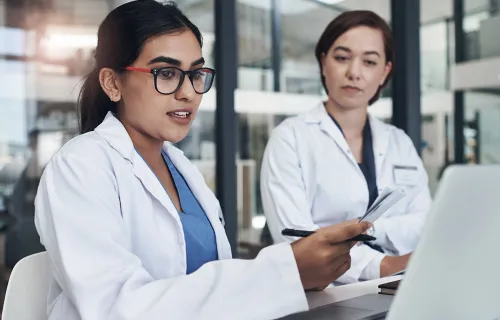 two medical professionals reviewing data at a monitor