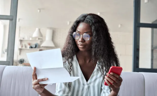 Women looking at paper holding phone